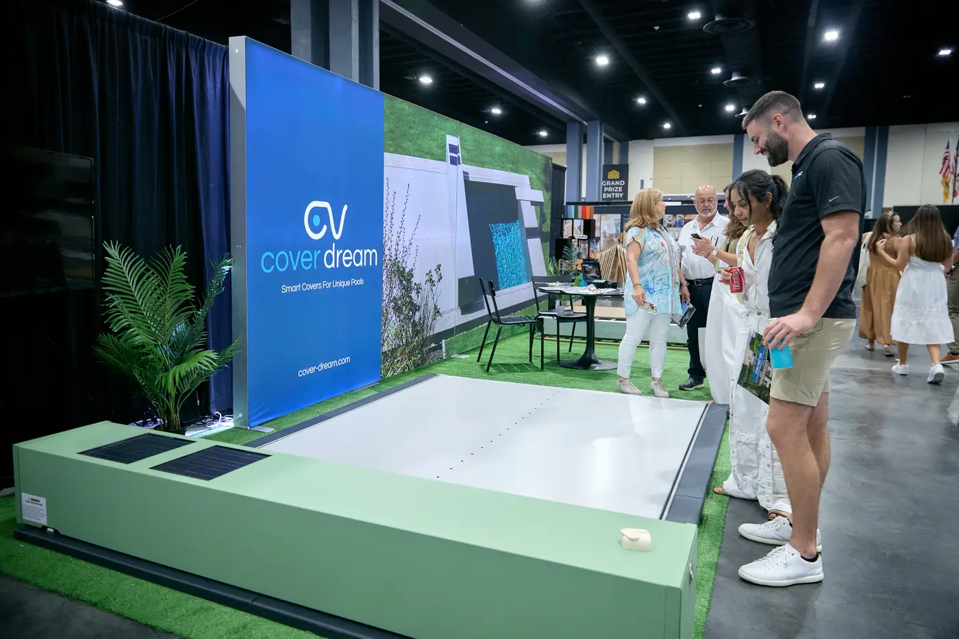 Visitors gathered around a smart pool-cover demo with open blue water