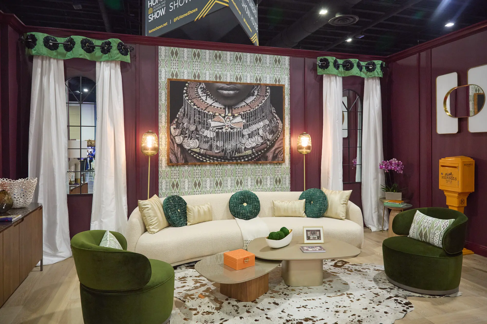 Burgundy designer room vignette with cream sofa and green velvet chairs