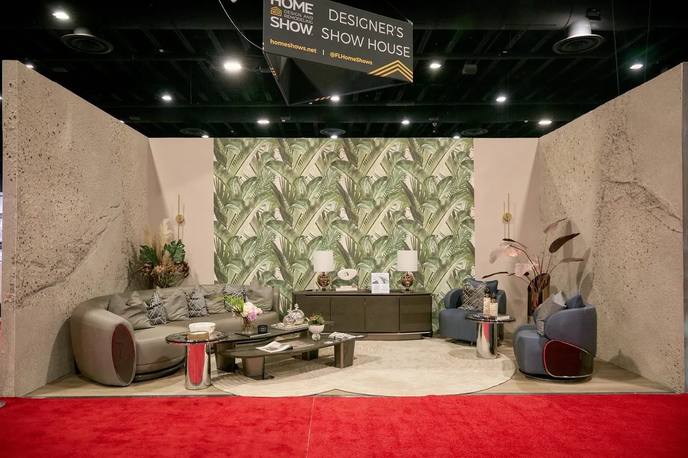 Designer's Show House lounge with a curved grey sofa and palm wallpaper