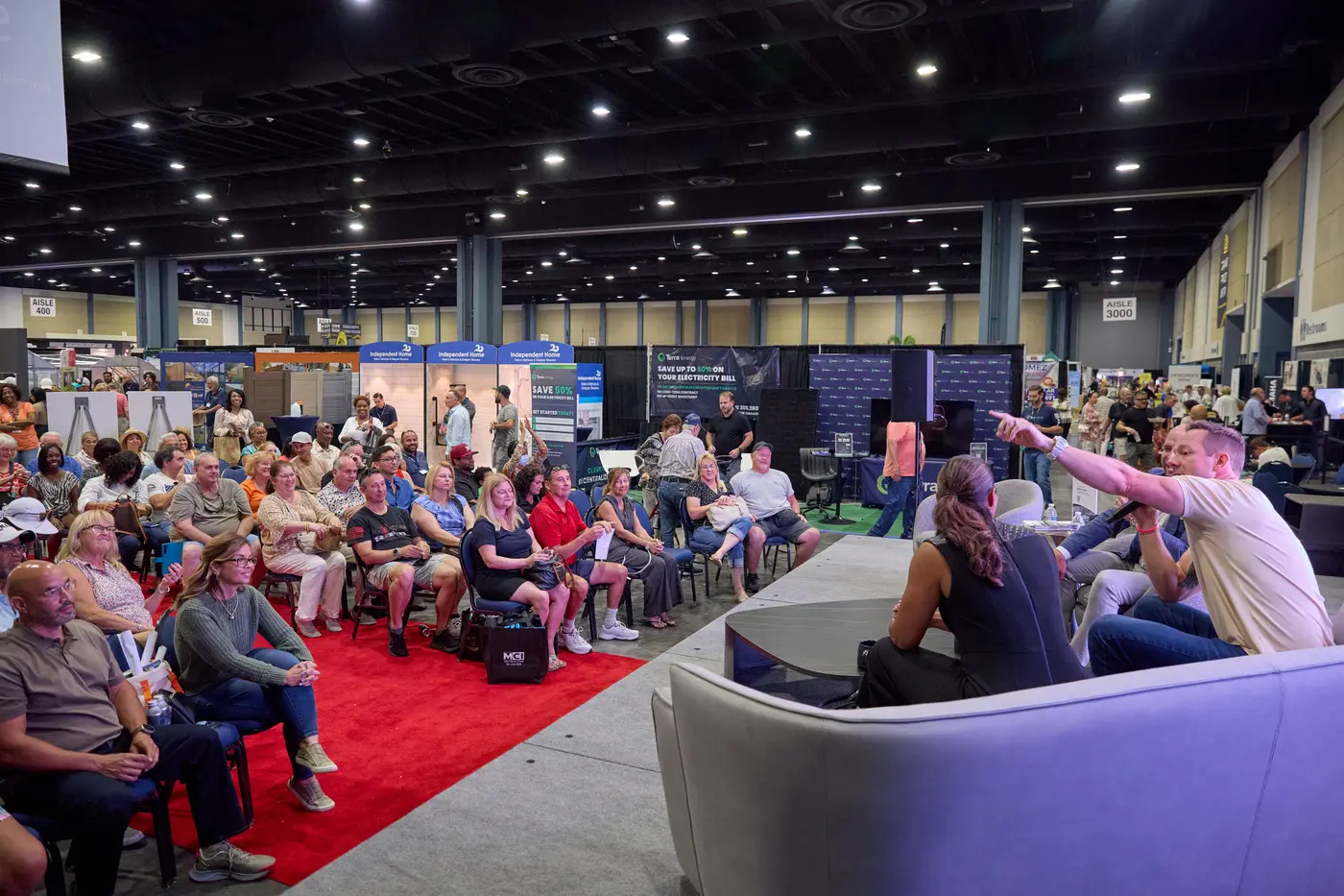 Speakers on the design stage in front of a packed seated audience