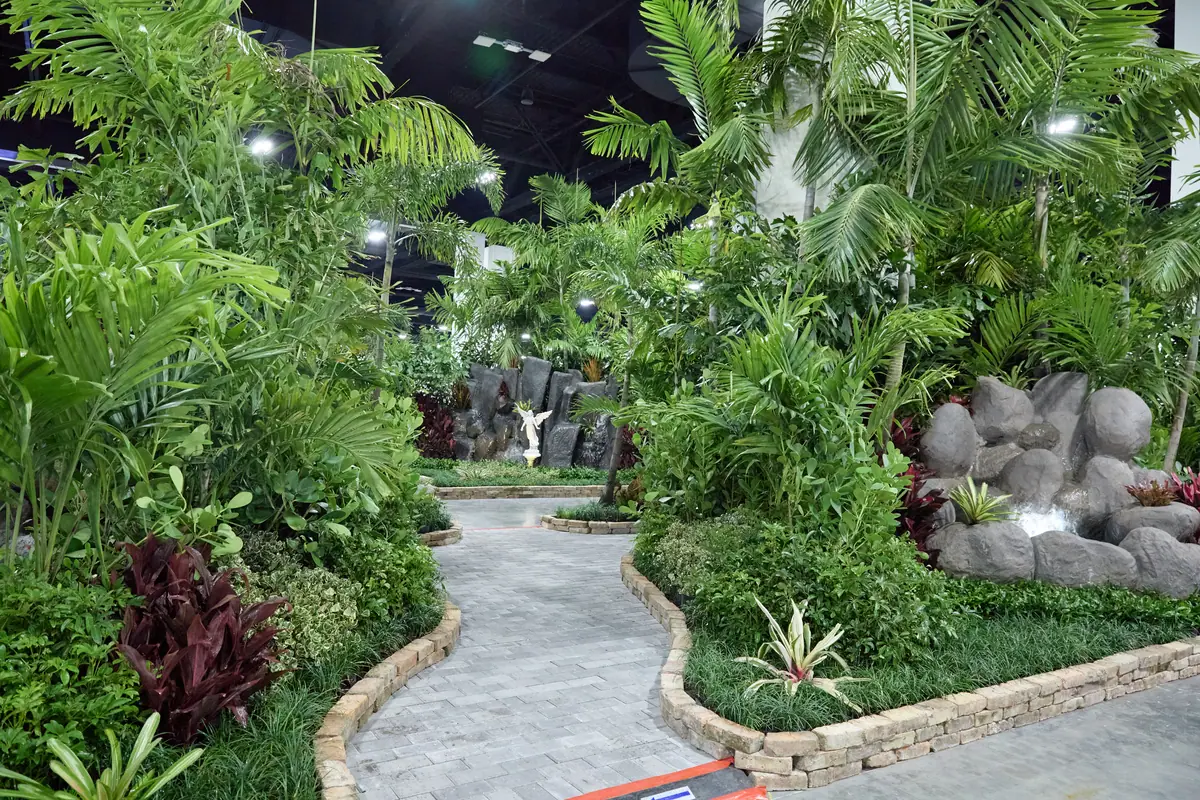 Indoor tropical garden exhibit with winding path, palms, and boulders at the Fort Lauderdale Home Show