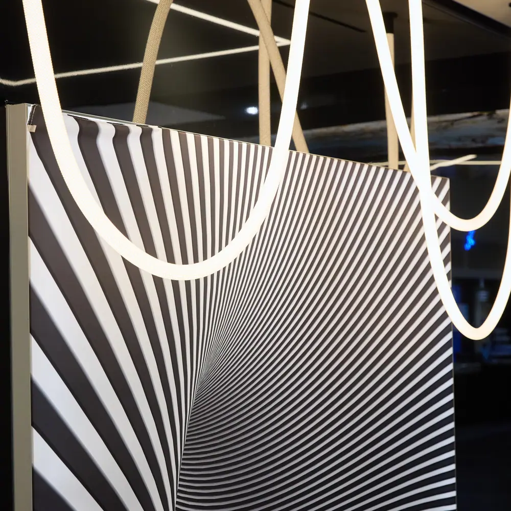 Dramatic black-and-white op-art interior panel with curved LED tube lighting at a home show booth