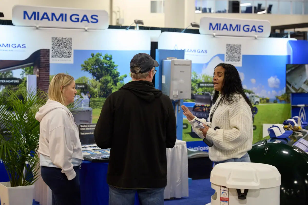 Miami Gas exhibitor rep engages a couple of attendees at a branded home show booth, brochures in hand