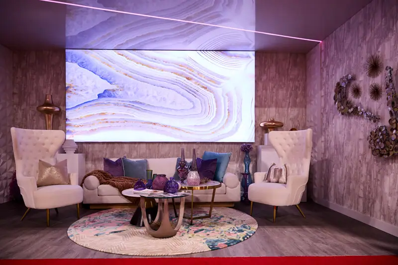 Glamorous VIP lounge exhibit with tufted wingback chairs, a cream sofa, and glowing agate LED wall