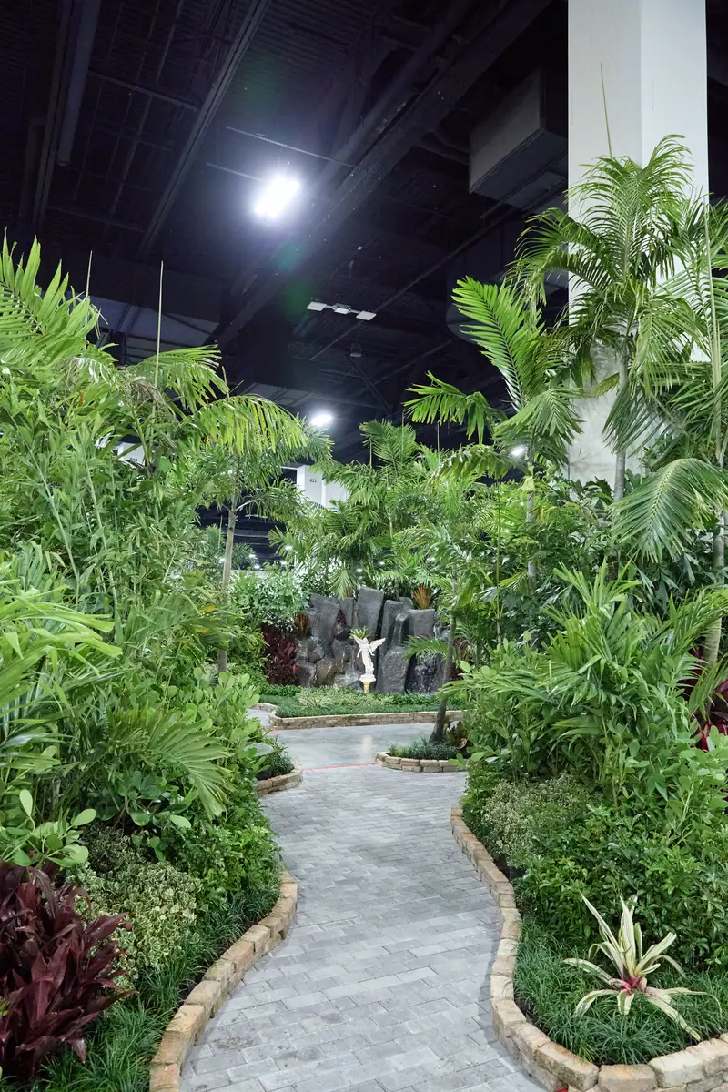 Indoor tropical garden path with palms and rock waterfall inside the home show convention hall