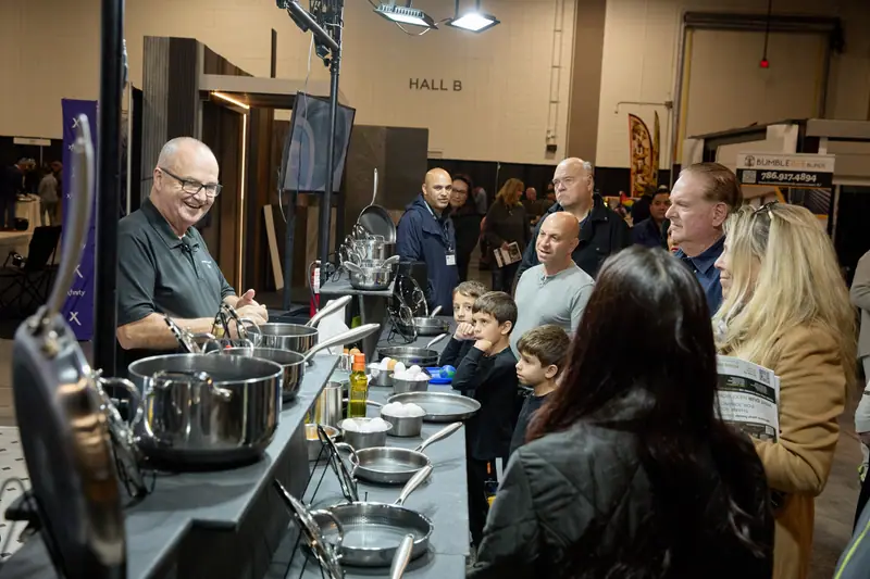 Cookware demonstrator entertains a crowd of families in Hall B at a home show culinary stage