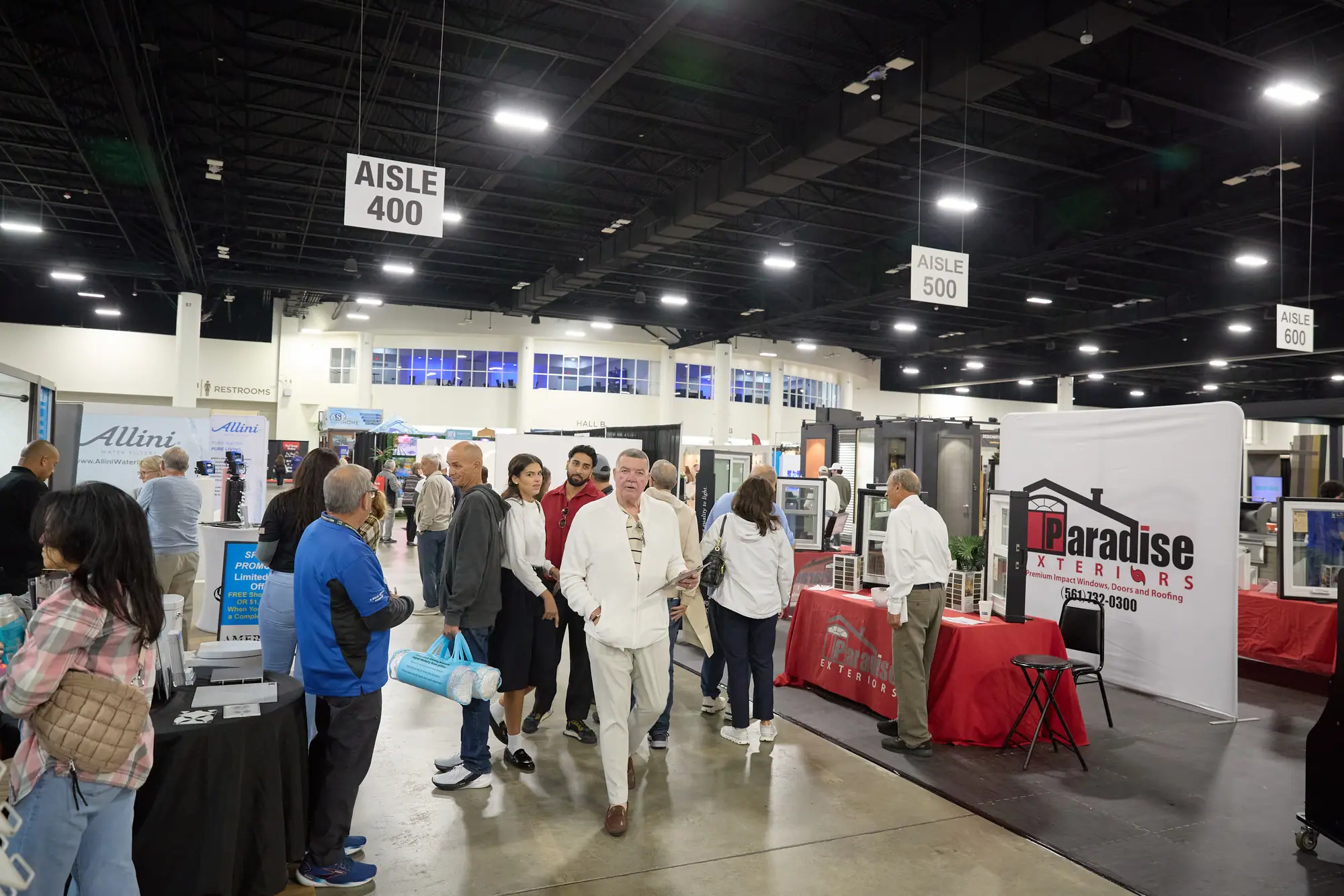 Busy Fort Lauderdale Home Show floor with crowds walking past booths at Aisles 400 and 500