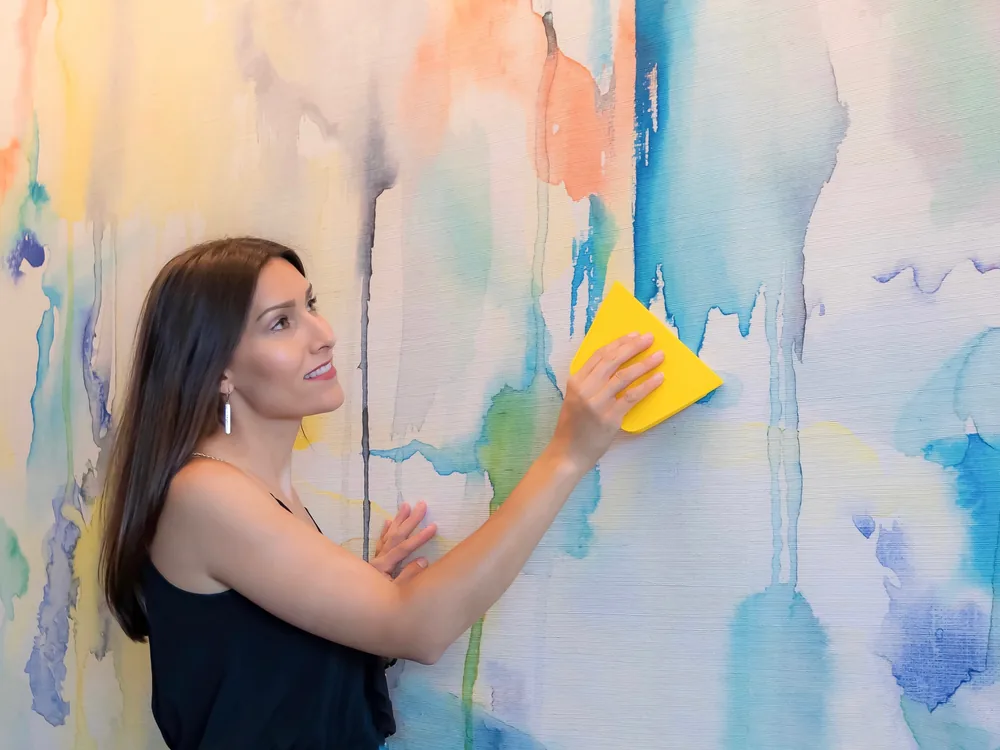 Katie Hunt squeegeeing a pastel watercolour mural flat against a wall