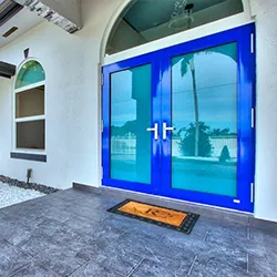 Vibrant blue French doors opening to a pool patio with palm trees