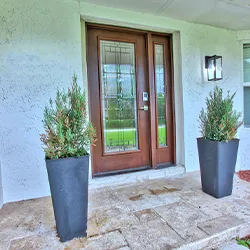 Craftsman-style wood entry door with sidelights and planters on stone porch
