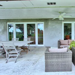 White sliding patio doors opening to covered outdoor lounge with pool view