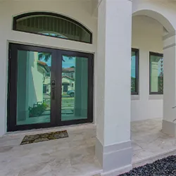 Dark-framed glass double entry doors on a Mediterranean-style home portico