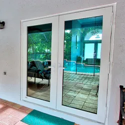 White hinged patio doors with pool and screened enclosure visible through glass
