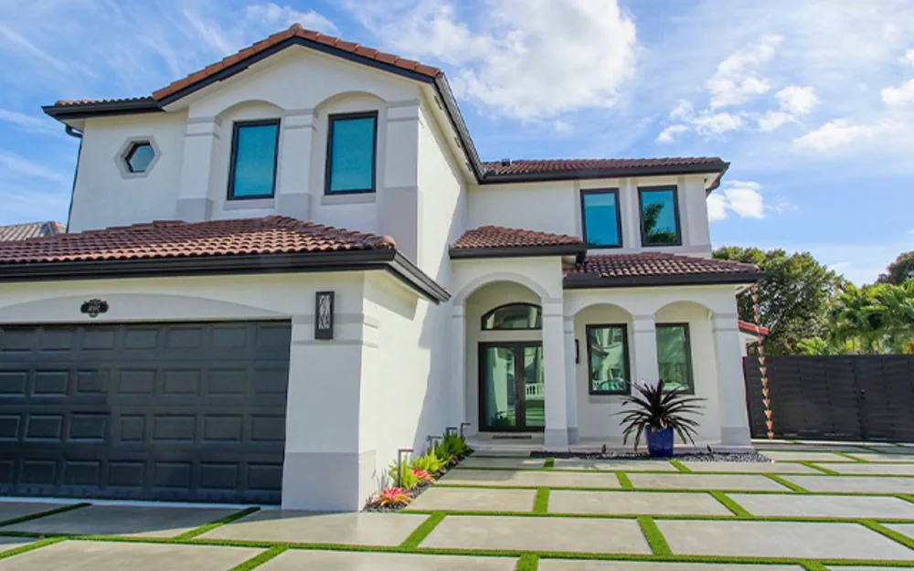 Two-story South Florida home with dark window frames and paver driveway