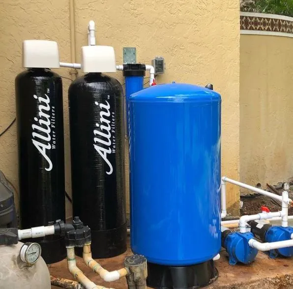 Two black Allini water softener tanks and large blue pressure tank on patio