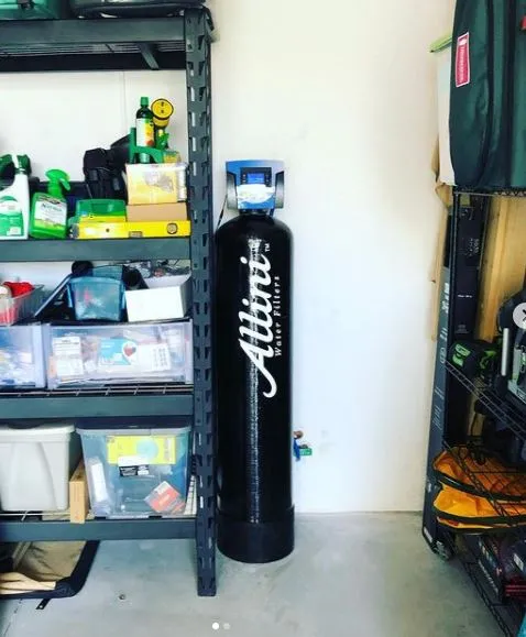 Allini whole-house water filter tank installed in a garage between storage shelves