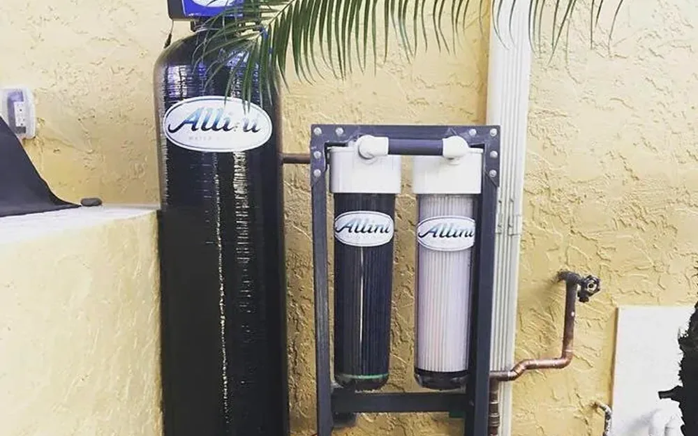 Allini water softener and dual-cartridge filter system on a stucco exterior wall