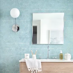 Light blue geometric tile bathroom with wood vanity, globe sconce, and frameless mirror