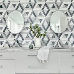 Double-vanity bathroom with grey geometric marble-look tile and dual oval mirrors