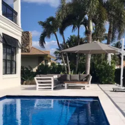 South Florida pool patio with white lounge furniture under a large market umbrella