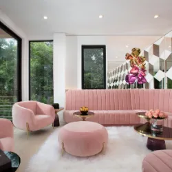Glam pink velvet living room with curved sofa, tufted chairs, and floral wall art