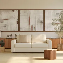 Modern cream sofa with walnut wood arms in minimalist room with abstract triptych art above sideboards