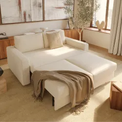 Cream sectional sofa-sleeper with pull-out chaise in warm beige room with olive tree and throw
