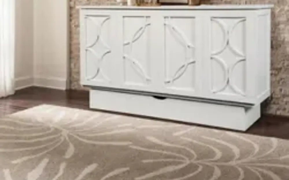 White lattice-panel murphy cabinet chest closed, shown on dark hardwood floor against brick wall