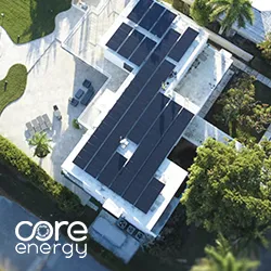 Aerial view of solar panel array on white flat roof with technician walking nearby, Core Energy logo