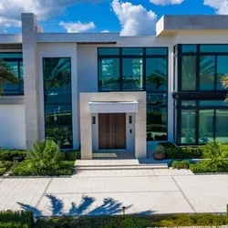 Modern two-story custom home exterior with glass entry, flat roof overhangs, and lush landscaping