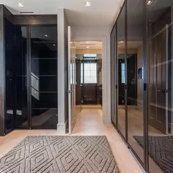 Custom home hallway with dark floor-to-ceiling glass-panel closets and geometric area rug