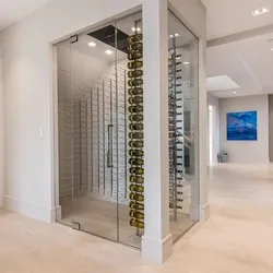 Glass-enclosed custom wine cellar with floor-to-ceiling wine racks in a luxury home hallway