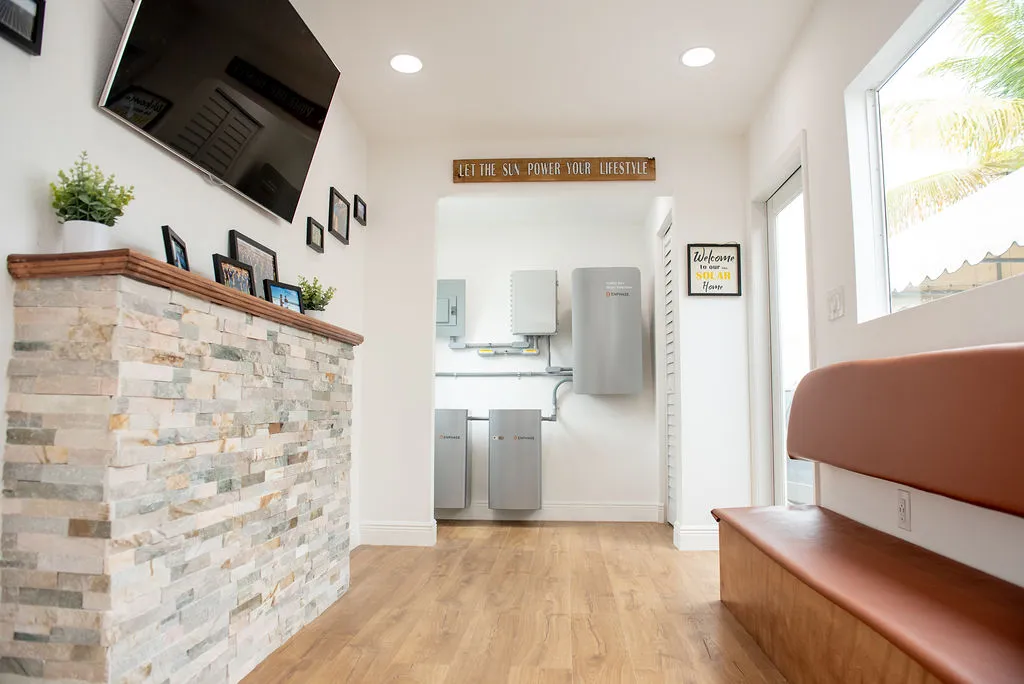 Solar showroom interior with Enphase battery display, stone fireplace wall, and 'Let the Sun Power Your Lifestyle' sign