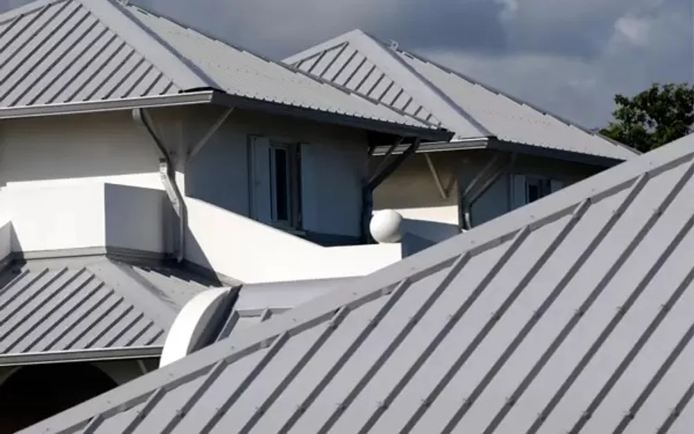 Multi-gable metal standing-seam roof on a white two-story Florida home