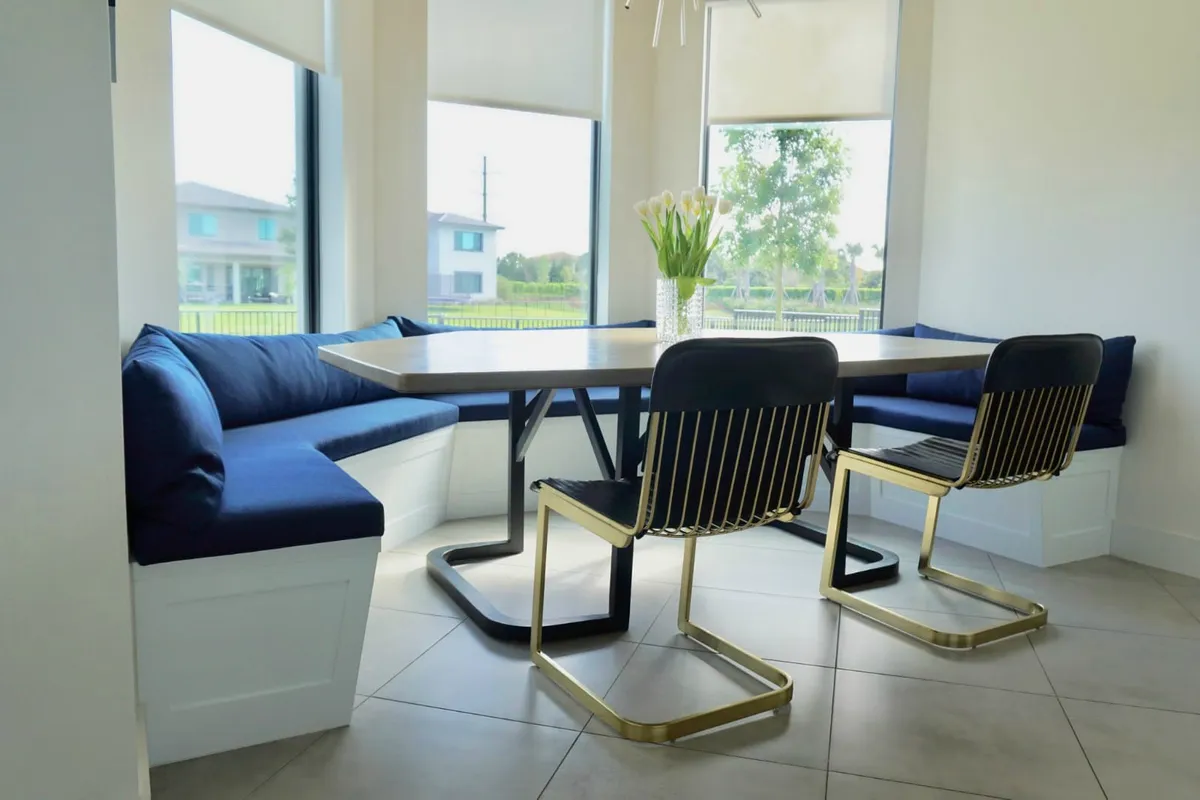 Corner dining banquette with navy cushions, modern gold dining chairs, and tulip centerpiece
