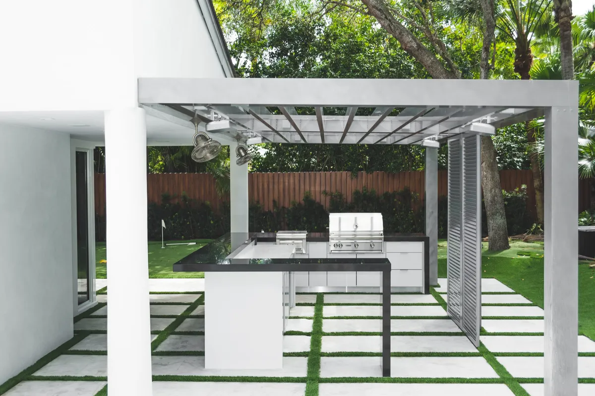 Modern pergola with outdoor kitchen island, grill, and putting green backyard