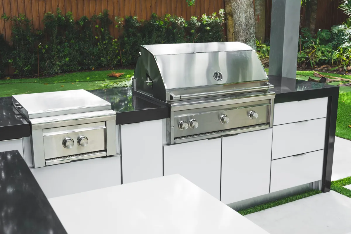 Stainless steel built-in grill and side burner on white outdoor kitchen island