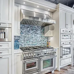 Luxury range with mosaic glass tile backsplash and white cabinetry in appliance showroom