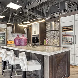 Open-concept kitchen showroom with large island, bar stools, and pendant lighting