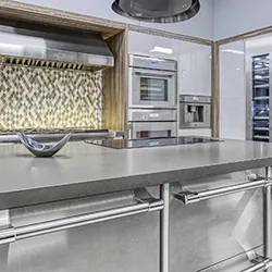 Stainless steel kitchen island cooktop with deep countertop and mosaic backsplash