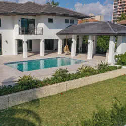 White two-story home with columned covered patio, pool, and tile deck