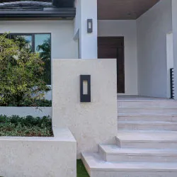 Contemporary home entrance with large-format limestone tile steps and wall sconce