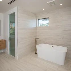 Spa-style bathroom with freestanding soaking tub and linear wood-look tile walls