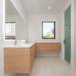 Modern bathroom with floating wood vanity, large mirror, and light wood-look tile floor