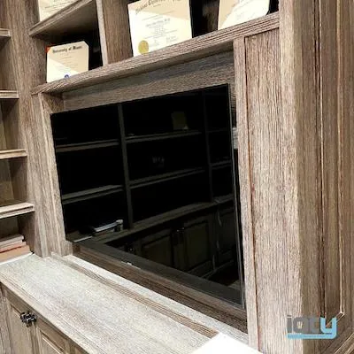 Hidden TV cabinet revealed inside a weathered wood bookcase wall unit