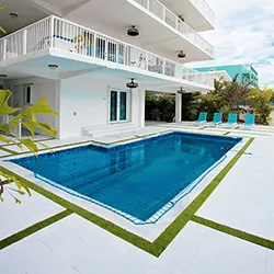 Two-story white Florida home with rectangular pool, blue pool cover, and artificial turf lawn