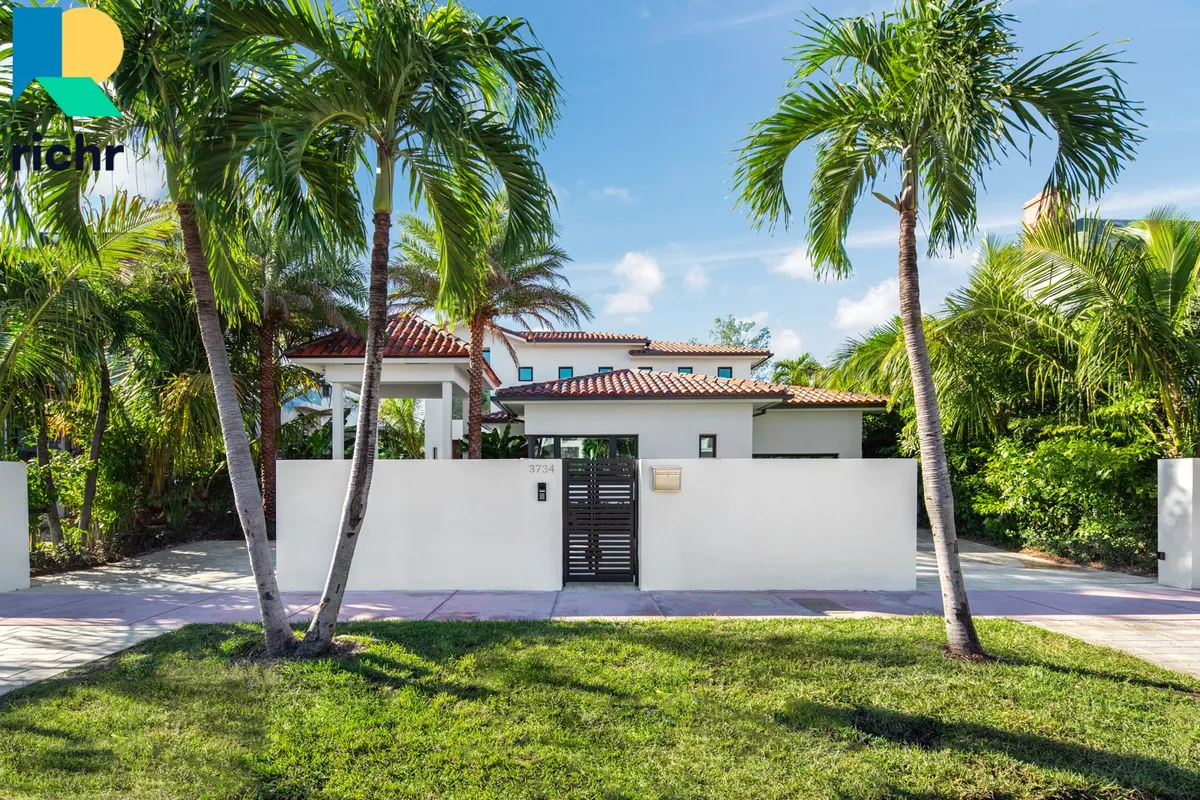 White Mediterranean-style home with palm trees and gated entry, Richr logo overlay