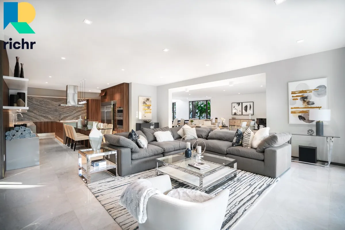 Bright open-plan living room with sectional sofa, glass coffee table, and open kitchen, Richr logo overlay
