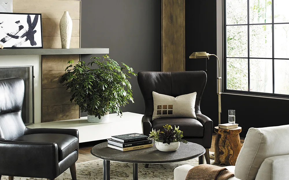 Moody living room with dark charcoal accent walls, leather wingback chairs, and fireplace