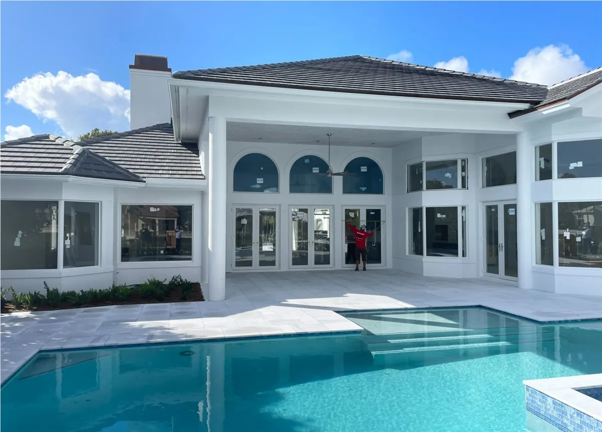 Installer fitting new impact windows and doors on a luxury pool-side home in South Florida